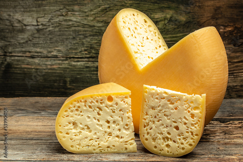 Photography Cheese wheel with cut a piece of cheese triangular shape from a large cheese head