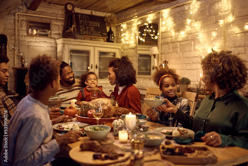 Happy African American extended family enjoying in lunch while celebrating Thanksgiving at dining table