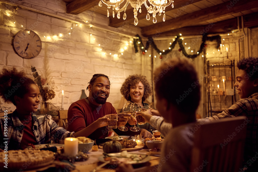 Cheerful black extended family toasting during Thanksgiving lunch at dining table.
