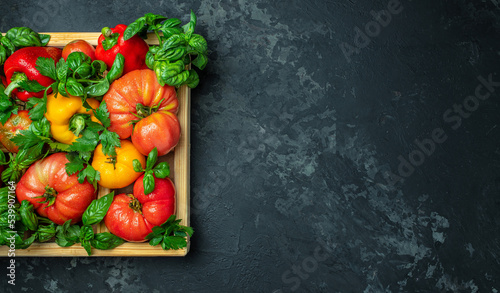 Various colorful garden tomatoes, bell peppers and spices. Ingredients for cooking on a dark background. Long banner format place for text, top view