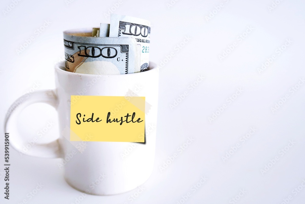 White coffee cup, cash dollars money on white copy space background with handwritten note Side Hustle, financial goal to make extra earning or second income from side business or part time job White coffee cup, cash dollars money on white copy space background with handwritten note Side Hustle, financial goal to make extra earning or second income from side business or part time job