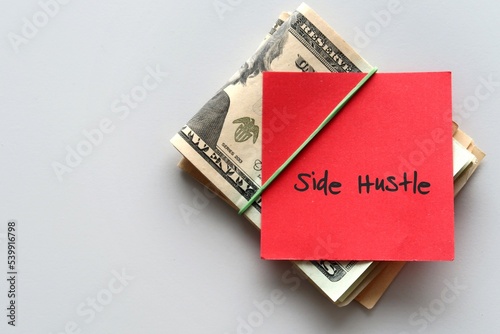 Dollars cash money and red paper note with text written SIDE HUSTLE - concept of financial planning - make more extra money from part time side hustle or second job to boost income photo