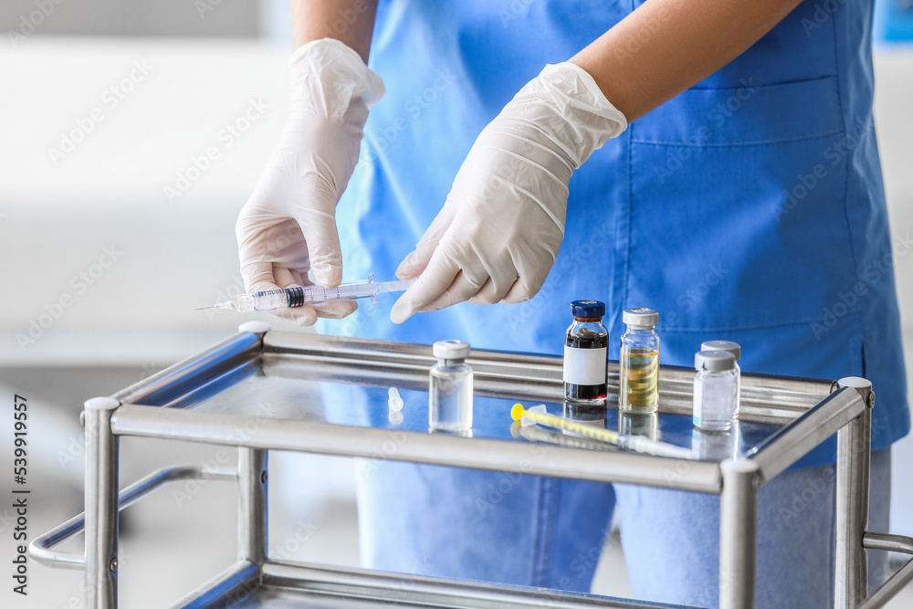 Female doctor with syringe near table in clinic, closeup Female doctor with syringe near table in clinic, closeup