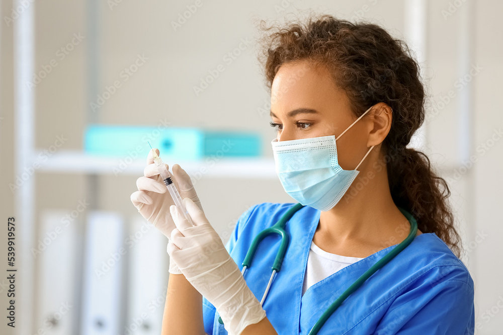 Female doctor in medical mask with syringe at hospital
