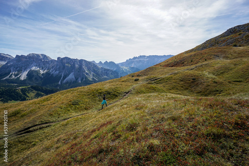 Sporty Young woman on mountain trail in Dolomites. Majestic view into the gardena valley  © grahof_photo