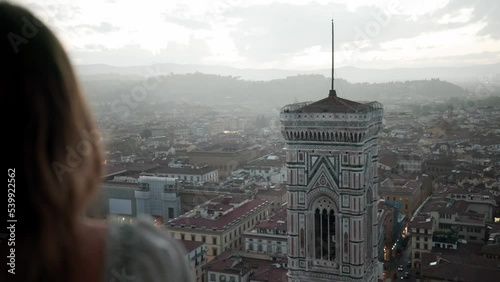 Lovely Woman Standing On Balcony Looking At The City Skyline With View Of Giottos Campanile Of Florence Cathedral In Italy. - Closeup, Pan Right  photo