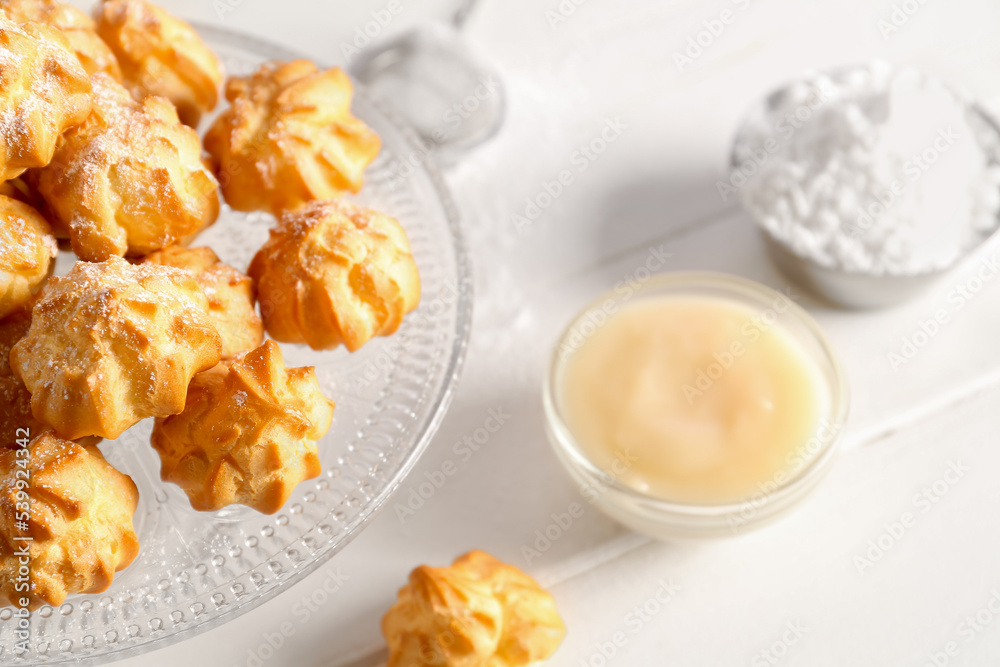 Dessert stand with delicious eclairs on light table, closeup