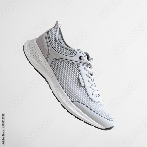 New sports shoes on light background. Close-up of sneaker flying in air, side view