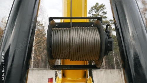 Electric drum hoist winch of mobile construstion crane. Windlass crab reel up steel cable coils on a building site.