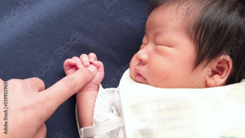 産後1か月0歳の新生児が小さな手で大人の指を握っている動画 photo
