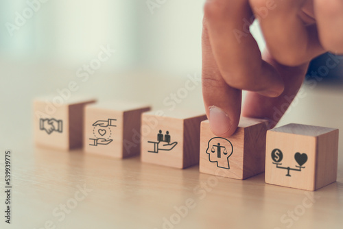 Business ethics concept. Ethics inside human mind. Business integrity and moral. Putting wooden cubes with ethics inside a head standing with other ethics icon. Company culture and sustainable success