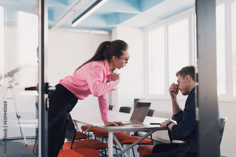 Emotional couple of young colleagues arguing in modern office. African-american business woman shouting at her sad man assistant, copy space, side view Emotional couple of young colleagues arguing in modern office. African-american business woman shouting at her sad man assistant, copy space, side view