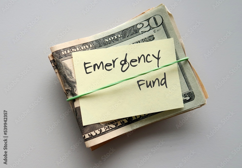 Dollars Money and paper note with text written EMERGENCY FUND - smart financial planning goal to build fund to be safety net expenses in unplanned life crisis or future distress Dollars Money and paper note with text written EMERGENCY FUND - smart financial planning goal to build fund to be safety net expenses in unplanned life crisis or future distress