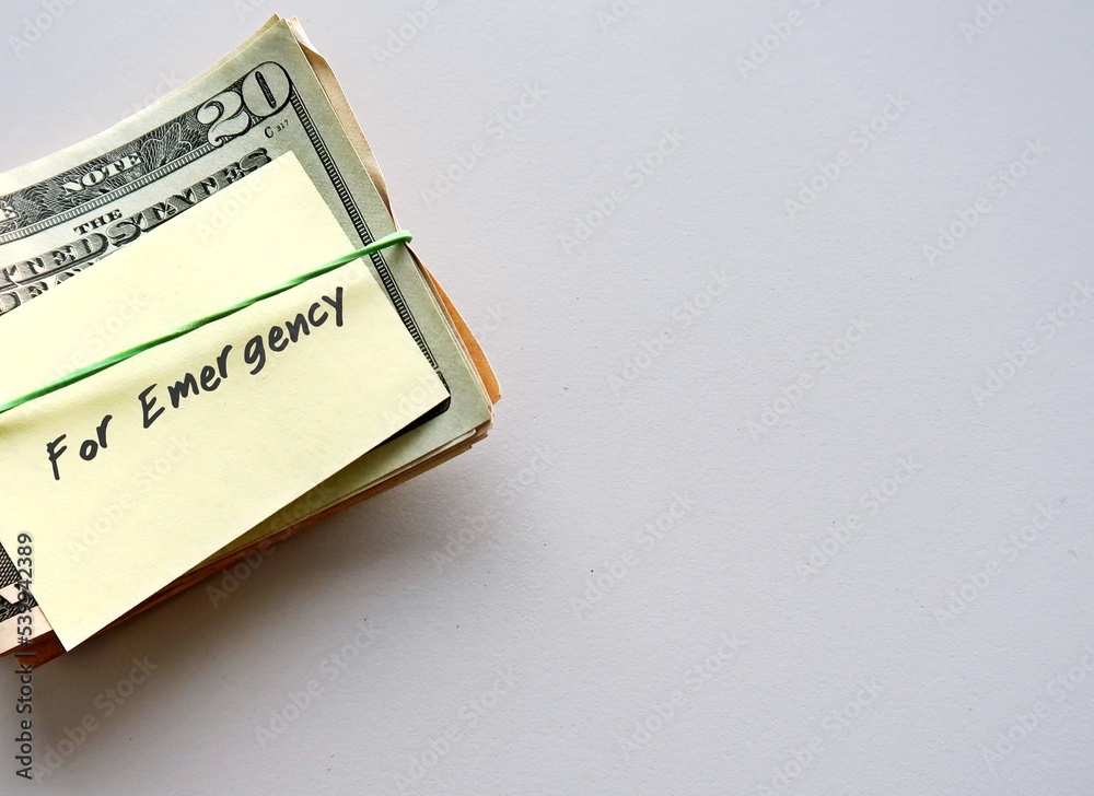Dollars Money and paper note with text written FOR EMERGENCY on copy space white background - smart financial planning goal to build fund to be safety net expenses in unplanned life crisis Dollars Money and paper note with text written FOR EMERGENCY on copy space white background - smart financial planning goal to build fund to be safety net expenses in unplanned life crisis