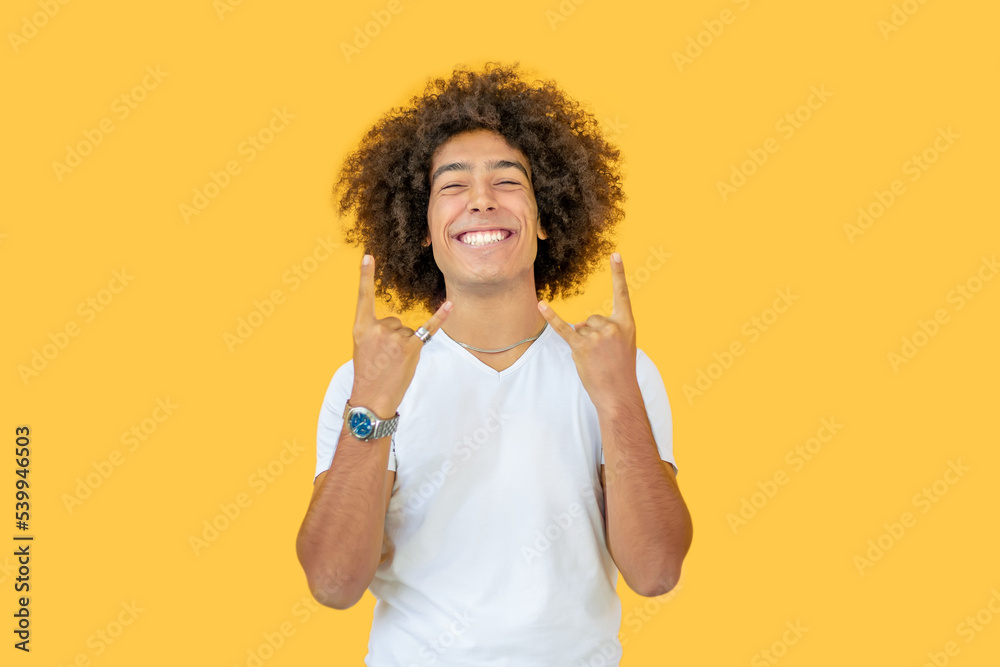 Smiling young men mixed race who rejoices in his success and victory showing you rock sign horned fingers wearing . Lucky man who is happy to reach the goal and goals. Positive emotions, feelings. Smiling young men mixed race who rejoices in his success and victory showing you rock sign horned fingers wearing . Lucky man who is happy to reach the goal and goals. Positive emotions, feelings.