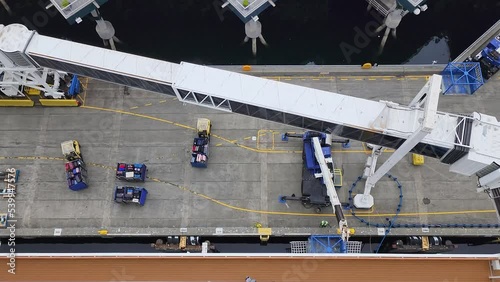 Dock workers loading luggage onto cruise ship viewed from above.