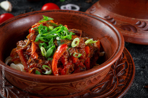 Traditional Kazakh dish Kuirdak. Aromatic roast of by-products, lamb meat with lots of onions and vegetables in a clay pot photo