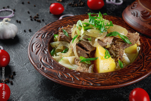 Traditional Kazakh dish beshbarmak with boiled dough, onions and mutton and beef in a clay pot