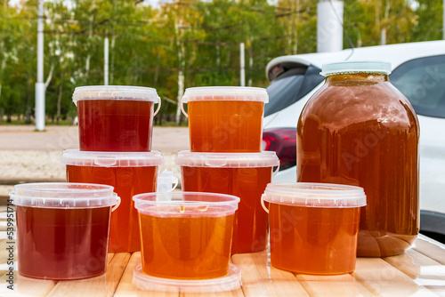 On counter there are jars and containers filled with multi-colored bee honey - beekeeping product. Autumn agricultural fair. Delicious honey sale.