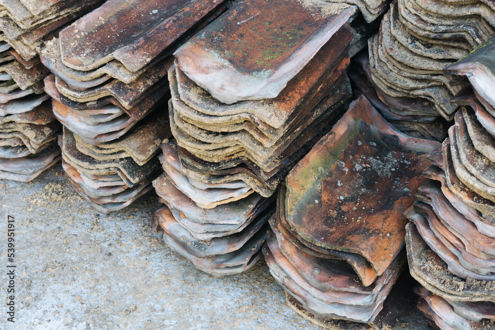 Roof demolition background. Ceramic roof tiles stacked. Grunge and used old roof tiles. Pile of dirty tiles background.