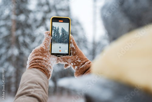 Happy woman making selfie with smartphone in beautiful snowy winter forest photo