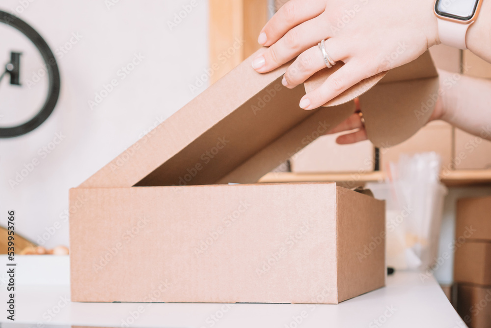 Cropped photo of woman hands packing, preparing parcel for delivery package to customers. Small business, online order Cropped photo of woman hands packing, preparing parcel for delivery package to customers. Small business, online order