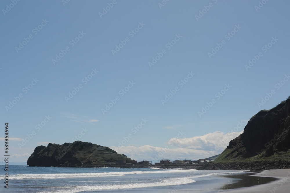 Picturesque seashore with rocks and beach on a sunny day with clear blue sky and calm ocean on Hokkaido, northern Japan, Asia Picturesque seashore with rocks and beach on a sunny day with clear blue sky and calm ocean on Hokkaido, northern Japan, Asia