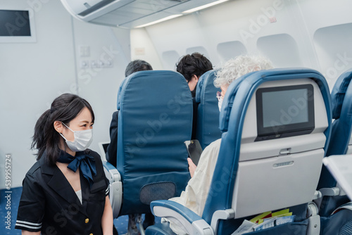 マスクをして機内サービスをする客室乗務員