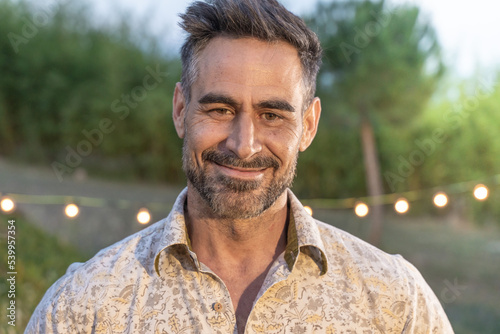 Good looking man portrait posing smiling in nature background in summer night.