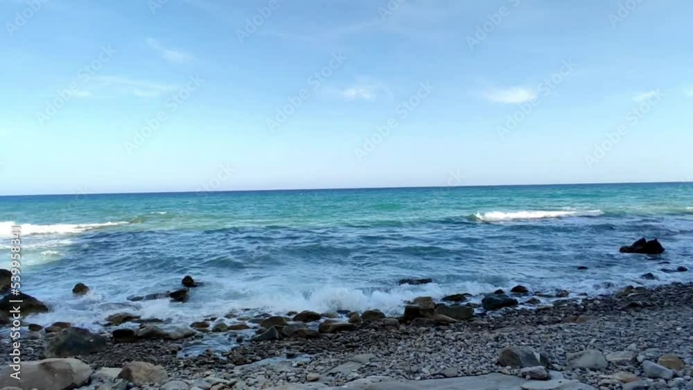 Girl walking on a rocky beach with waves in the background