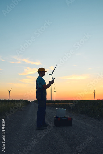 Engineer mechanic using drone for inspection in a windmill farm park.