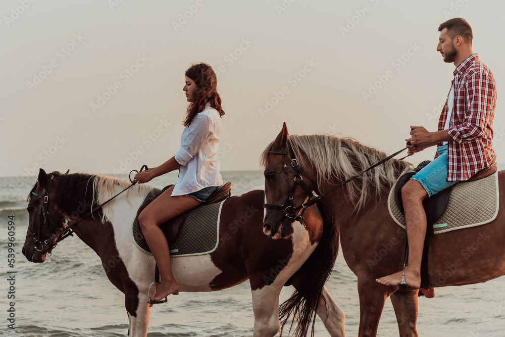 A loving couple in summer clothes riding a horse on a sandy beach at sunset. Sea and sunset in the background. Selective focus A loving couple in summer clothes riding a horse on a sandy beach at sunset. Sea and sunset in the background. Selective focus