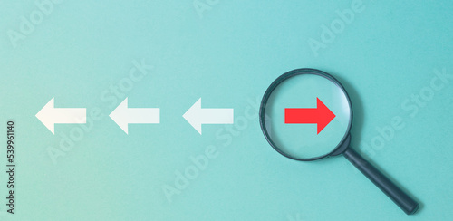 Red arrow inside a magnifying glass, concept of different directions, business discrepancy.