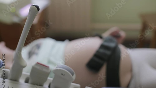 Ultrasound diagnostic sensors against the background of the belly of a pregnant woman who does cardiotocography. The concept of fetal ultrasound during pregnancy, medical examination. photo