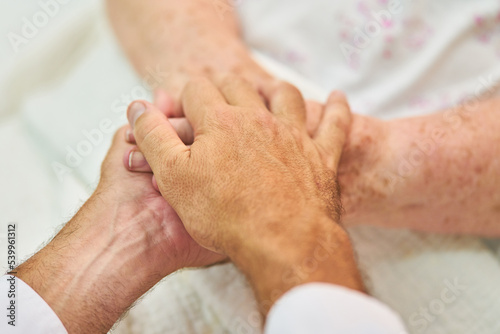 Altenpfleger hält Hände einer Patientin als Trost