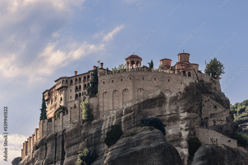 Bottom view of Varlaam Monastery, stone wall, Byzantine-style inner buildings exhibiting  illustrated manuscripts in sacristy, and beautiful arched stone gazebo on panoramic terrace, Meteora, Greece
