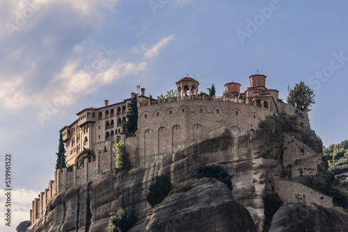 Bottom view of Varlaam Monastery  stone wall  Byzantine-style inner buildings exhibiting  illustrated manuscripts in sacristy  and beautiful arched stone gazebo on panoramic terrace  Meteora  Greece