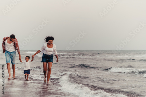 The family enjoys their vacation as they walk the sandy beach with their son. Selective focus 