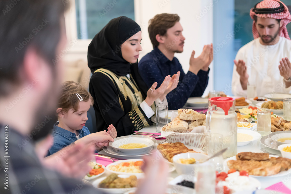 Muslim family making iftar dua to break fasting during Ramadan.