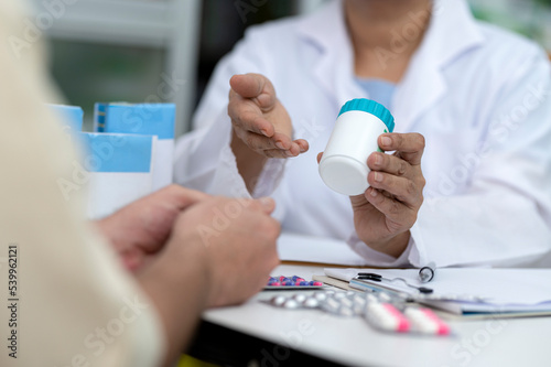 Indian asian elderly female pharmacist advises caucasian male medicine to treat ailments.