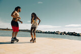 Cheerful couple roller skating outside. Fun sexy boyfriend and girlfriend enjoy in sunny day.