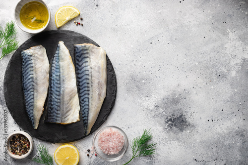 seafood background with ingredients for cooking. Raw fresh fillet mackerel fish with aromatic herbs, spices, lemon and olive oil on kitchen table. place for text