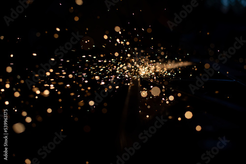 Sparks in dark. Stream of lights on black background. Metal crushing. High temperature.