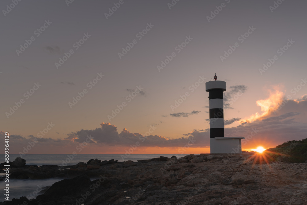 Sonnenuntergang mit Sonnenstern über dem Leuchtturm Sa Punta Plana Mallorca Balearen