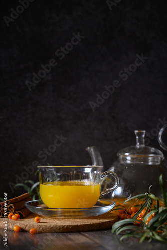 Tea of sea-buckthorn berries with branch on dark wooden background