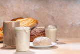 Healthy lifestyle, gluten free fermenting diet. Homemade sourdough. Active bubbly rye, wheat, oat sourdough with different flour and fermentation methods, in glass jars, with raw dough and baked bread