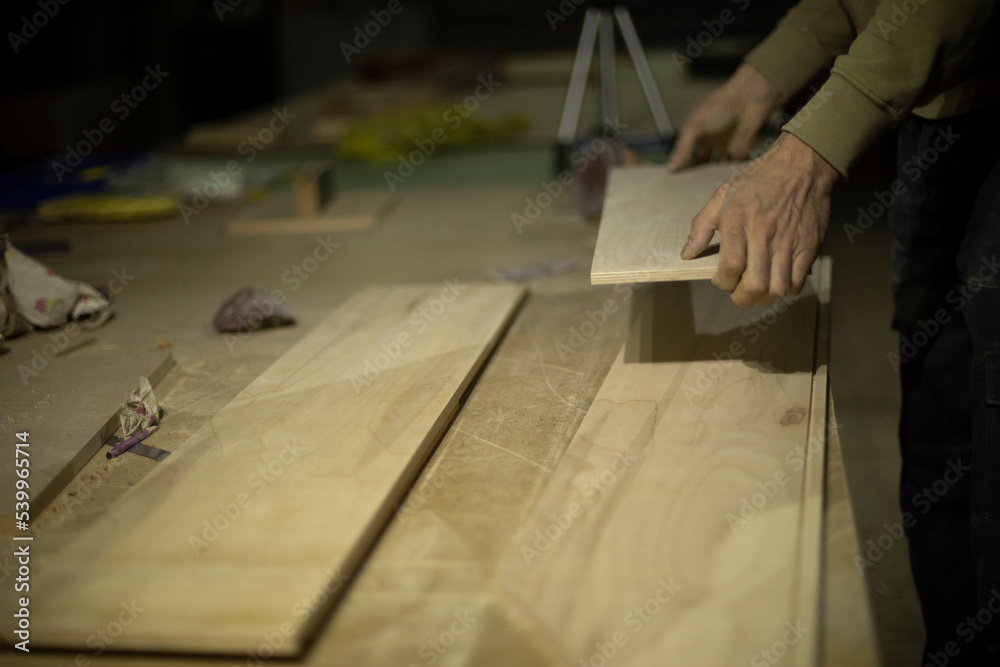 Carpenter holds tree. Worker chooses board. Details of carpentry workshop.