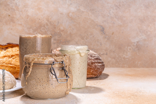 Healthy lifestyle, gluten free fermenting diet. Homemade sourdough. Active bubbly rye, wheat, oat sourdough with different flour and fermentation methods, in glass jars, with raw dough and baked bread photo