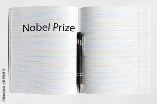 The inscription NOBEL PRIZE on a white sheet notebook.Nobel prize in literature. A pen is lying nearby.White background.Selective focus,close-up,copy space. photo