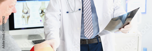 Fotografija Physician wear uniform and examining patient scan, touch mans knee